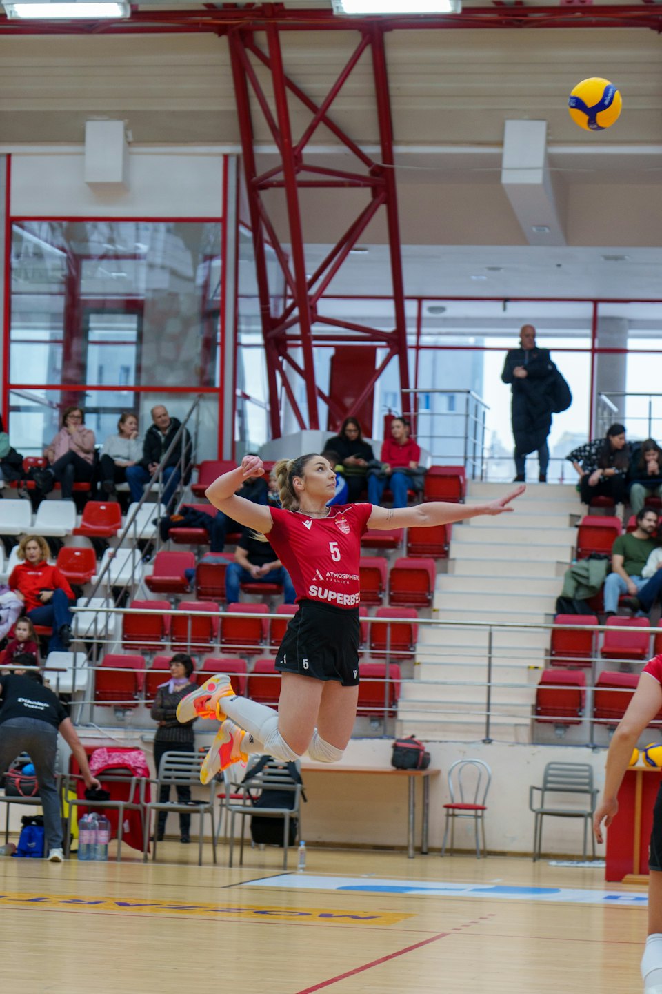 A volleyball player jumps to hit a ball during a match.