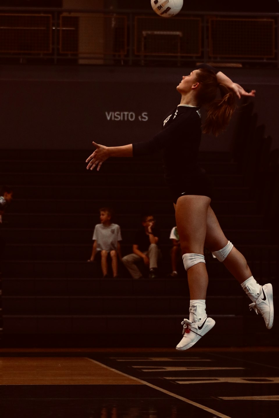 Volleyball player jumps to spike the ball on an indoor court.