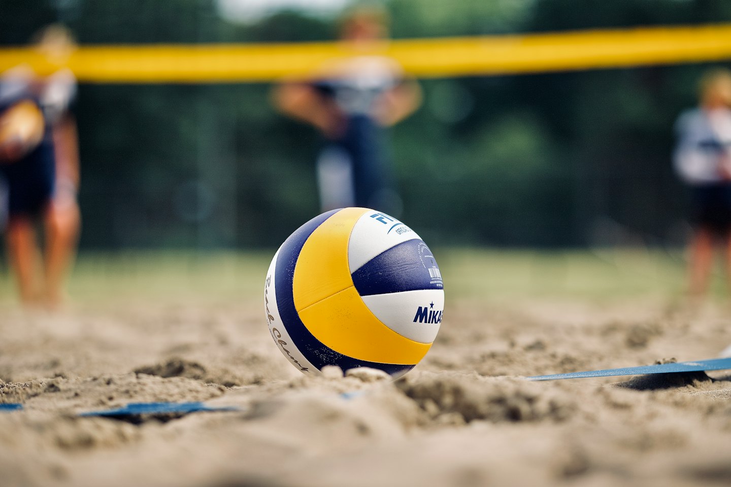 Volleyball resting on a sandy court.